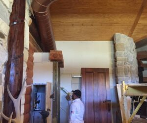 A technician applying caulk to seal something on a wall.