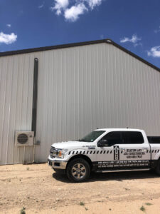 A truck next to a building with a commercial or residential HVAC system.